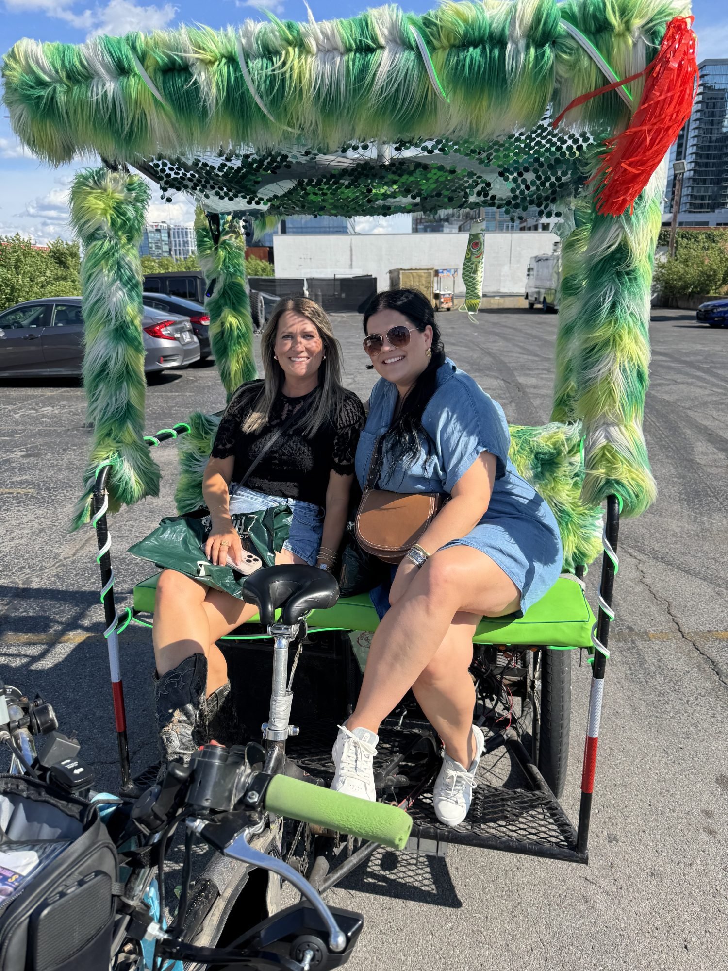 Ladies riding on a green pedicab from Local Bike Taxi in Nashville. 