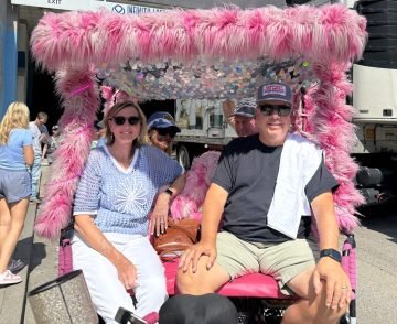 Two couples riding on a bright pink pedicab, with a giant sequin canopy.
