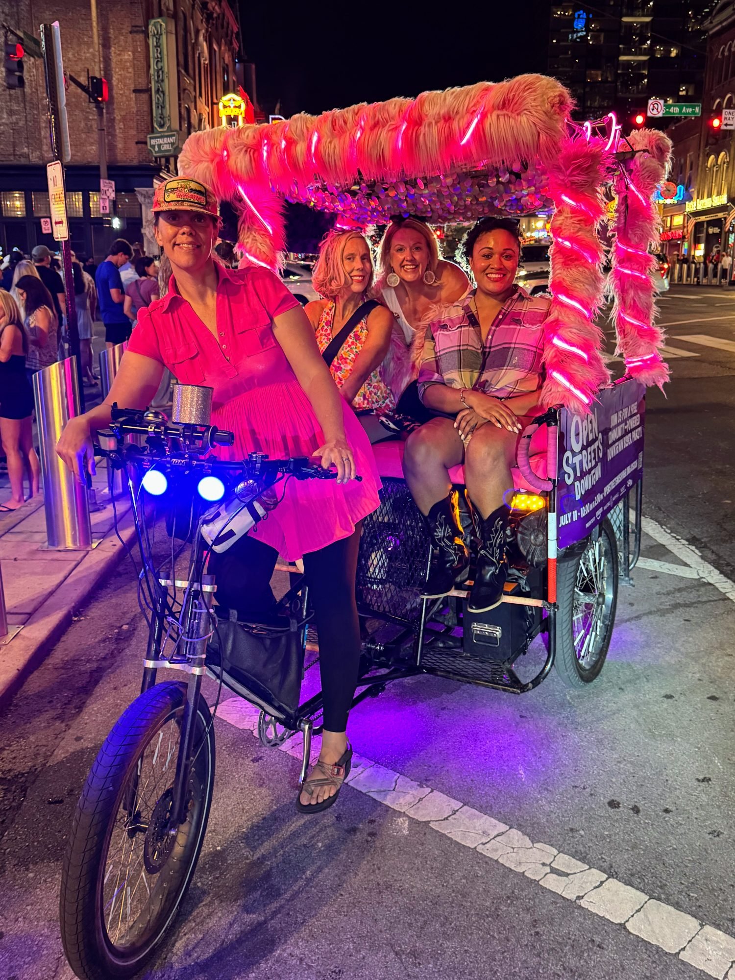 Pink pedicab on Broadway with three female guests.