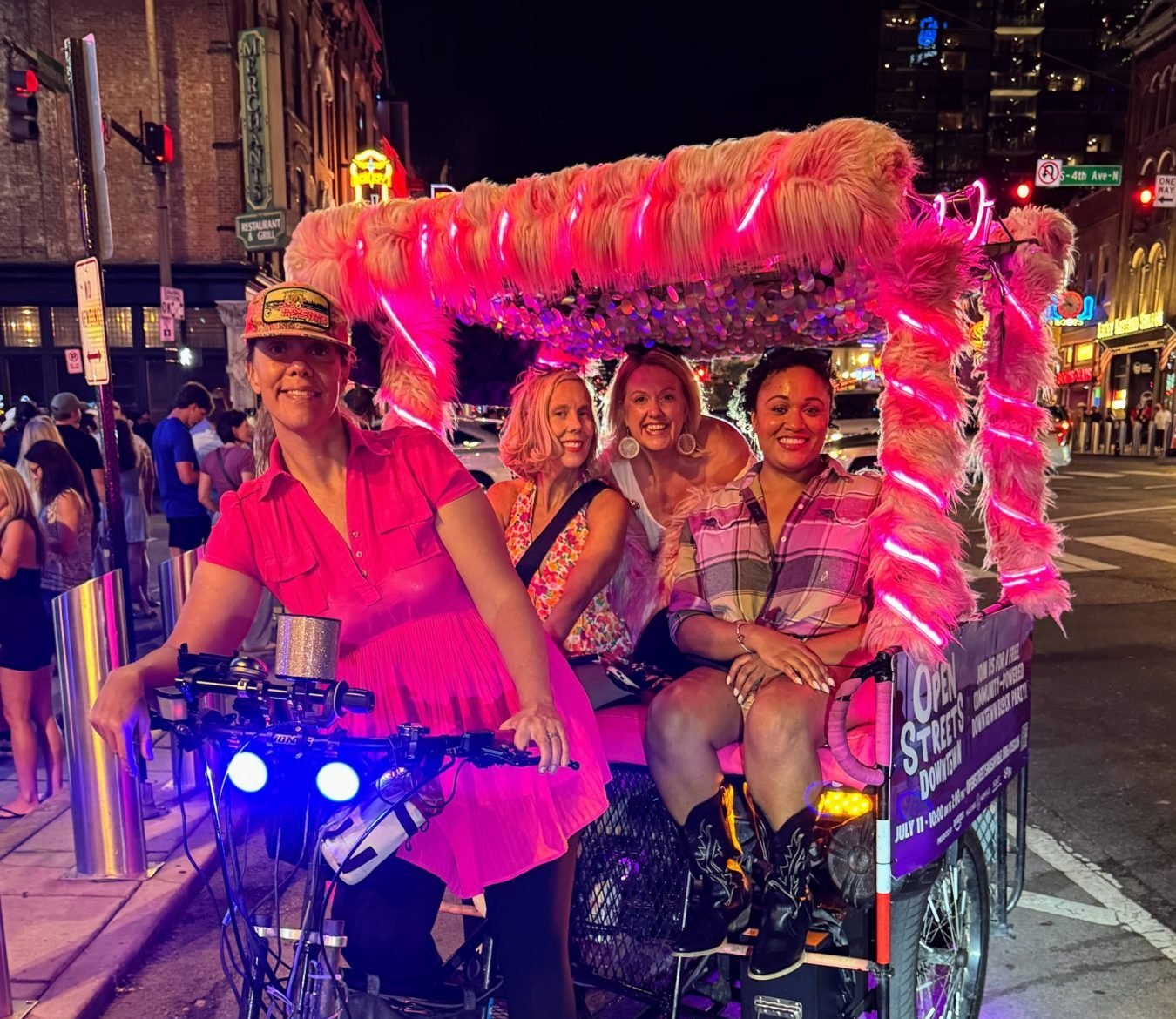 Pink pedicab on Broadway with three female guests.