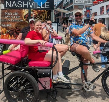 Local bike taxi Pink pedicab with three ladies on a ride from the Music City Marathon, near the John Seigenthaler Pedestrian Bridge