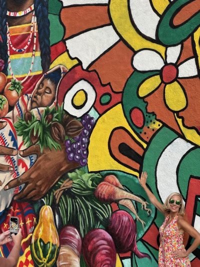 A girl posing in front of a tropical mural in Nashville.