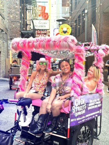 Ladies riding in a pink pedicab in Printers Alley, Nashville
