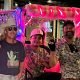 Guys riding on a hot pink neon pedicab with pink fur with giant life sized Alan Jackson Cut out.